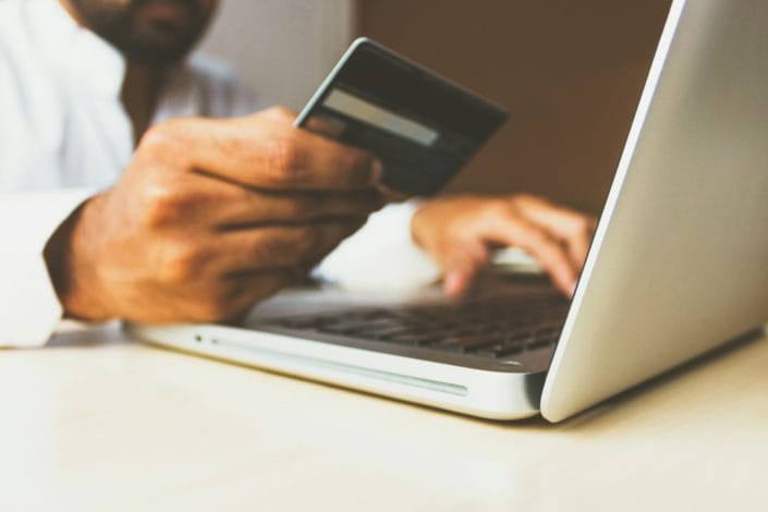 rupixen com QHmzKeQ unsplash Pay online - man holding card in front of laptop