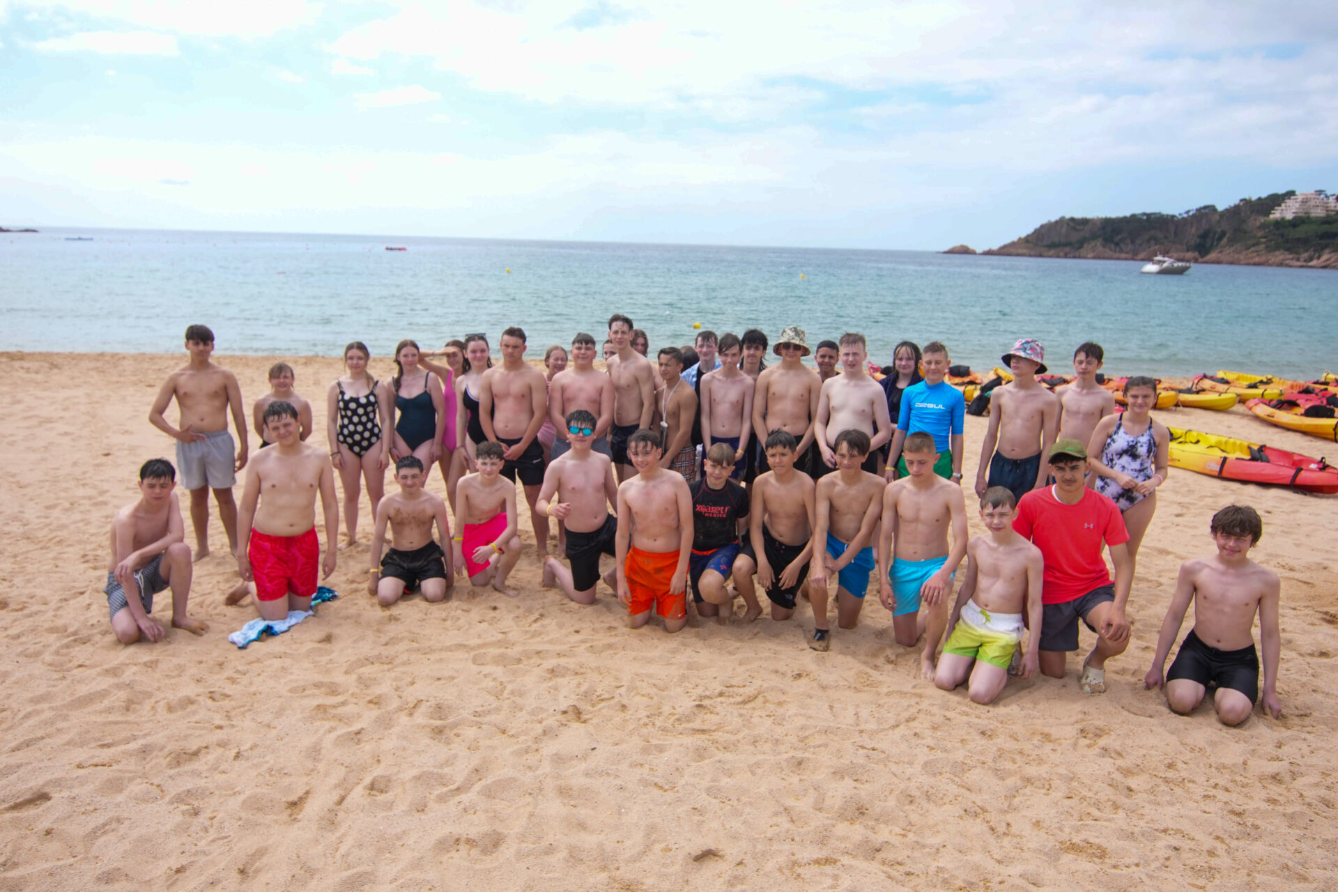 School group on a beach with kayaks during an overseas watersports trip