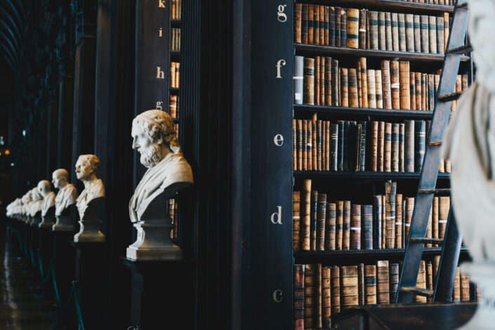 British Library Historic library interior featuring shelves of antique books, marble busts of literary figures and a wooden ladder, highlighting centuries of literary history and learning.